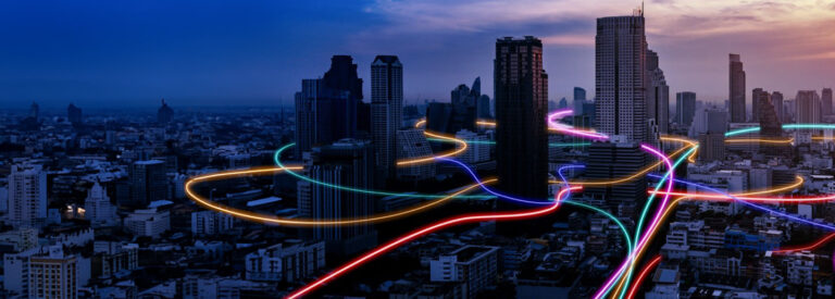 smart city skyline with multi colored neon lines running through at night.