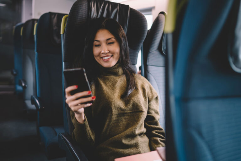 woman sitting on a shuttle bus holding her cell phone