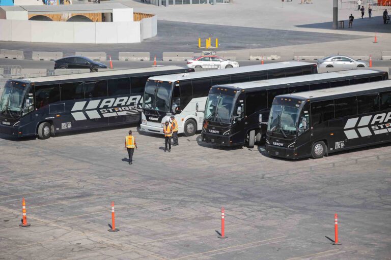 4 shuttle busses in parking lot with TMS workers