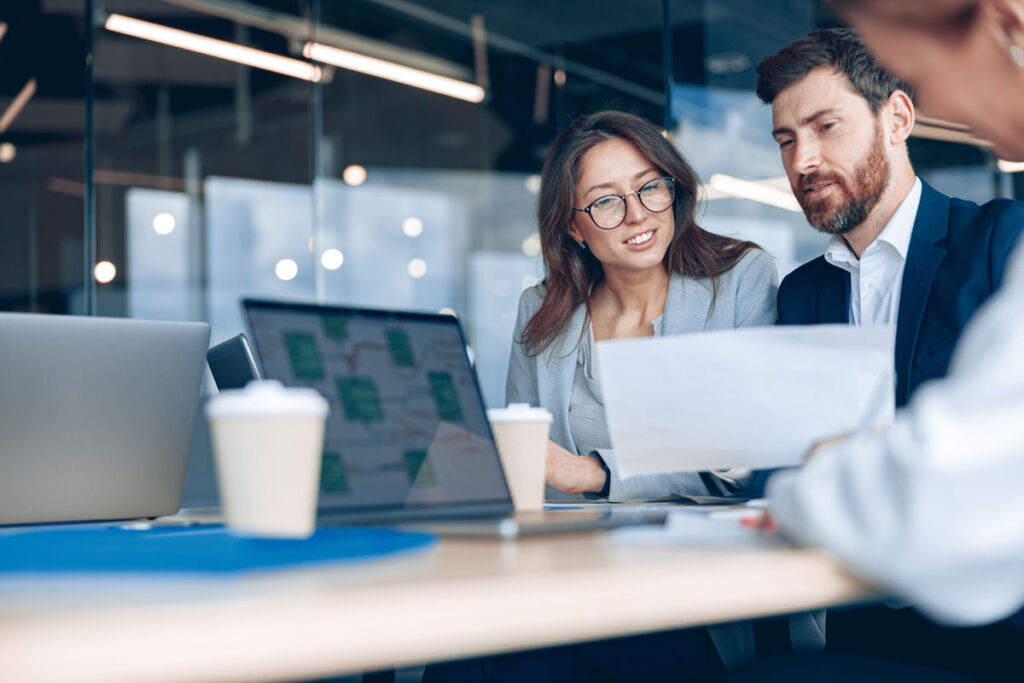 2 workers in a conference room looking at their laptops