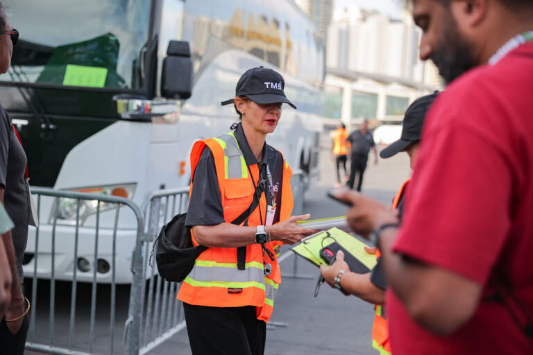 TMS employee talking with guests outside near shuttle bus