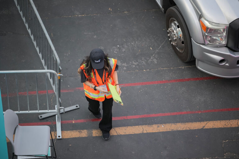 overview shot of TMS worker with clipboard in hand in parking lot