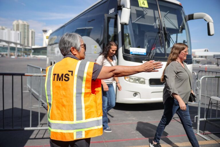 TMS worker assisting attendees outside of the shuttle bus